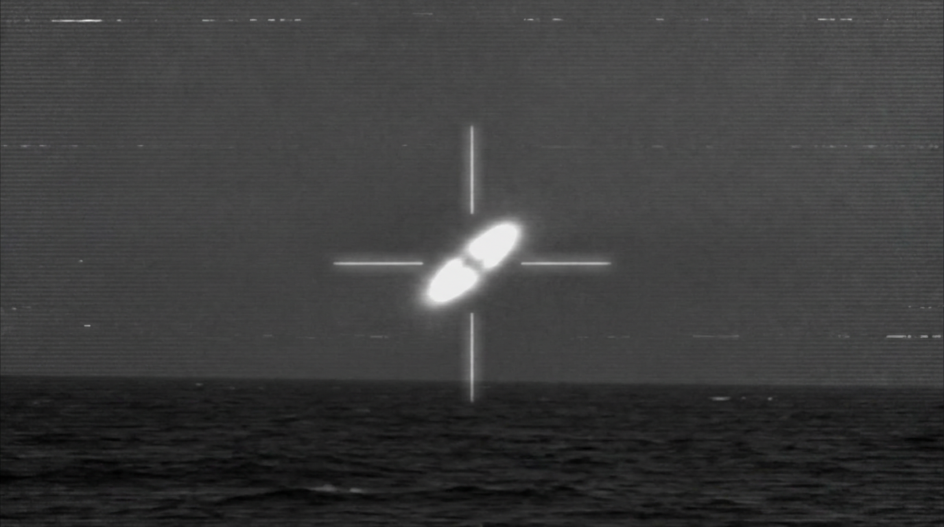 Simulated infrared targeting pod view showing a bright oblong object tracked by crosshairs against a dark background, resembling declassified Navy FLIR footage