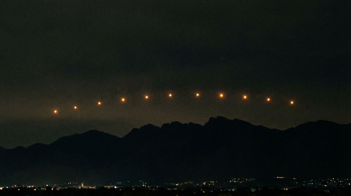 Illustration of the stationary amber lights hovering in a row above the Estrella Mountains near Phoenix, viewed from a suburban rooftop at night